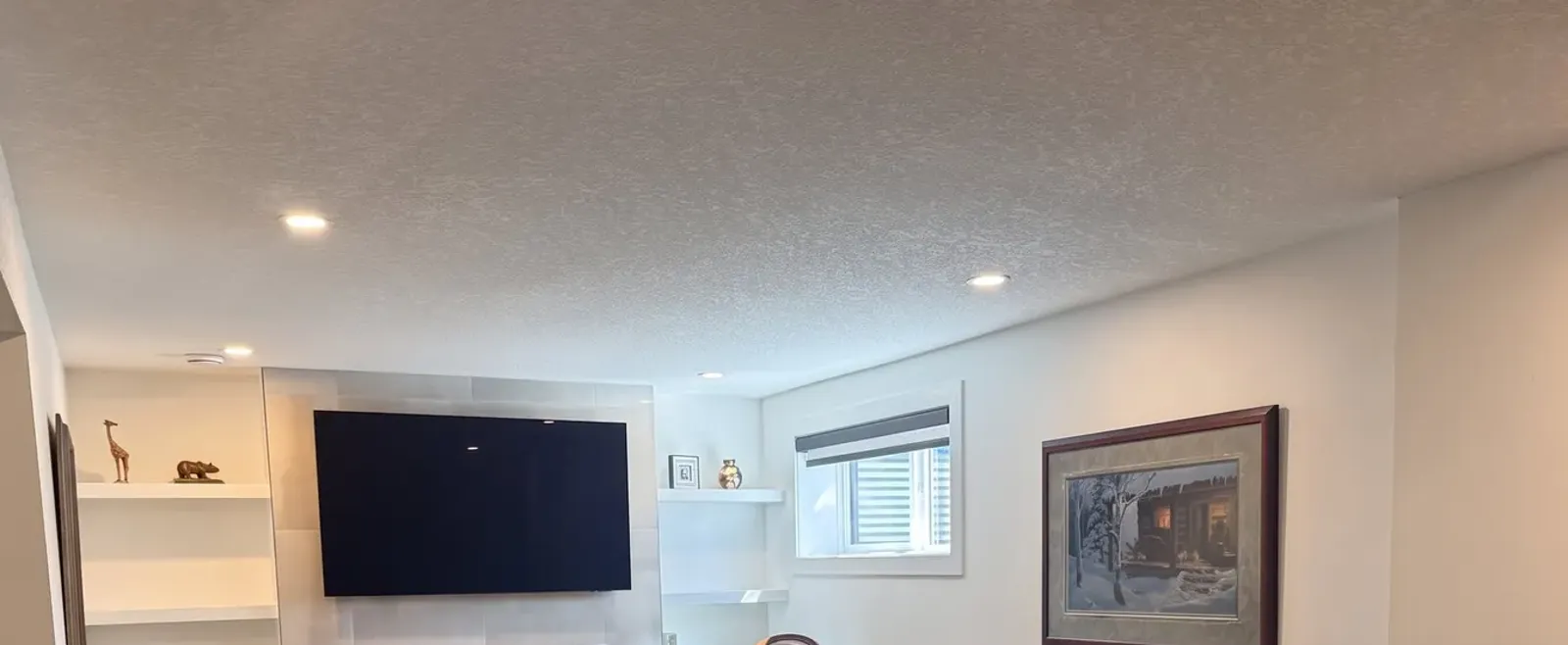 A freshly painted basement ceiling with recessed lights and clean lines where ceiling meets wall