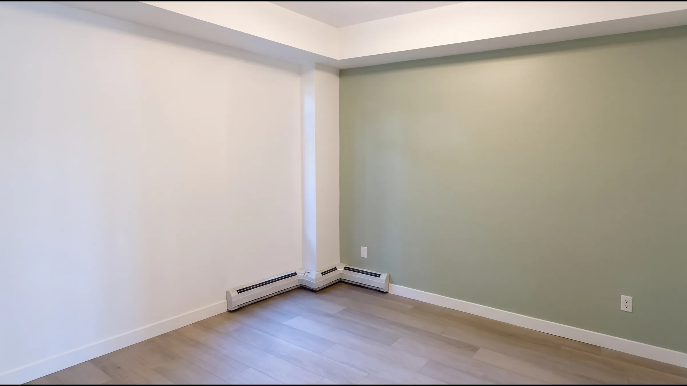 A bedroom with a sage green feature wall and crisp white trim