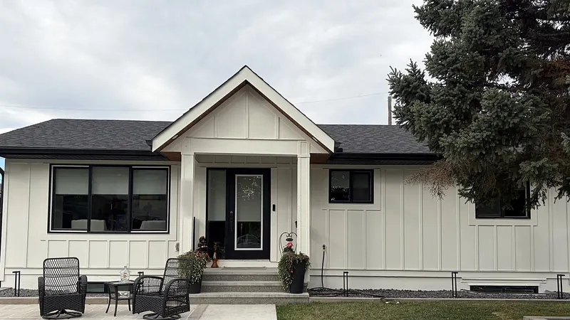 A bungalow freshly repainted in white board-and-batten with black window frames and a black front door