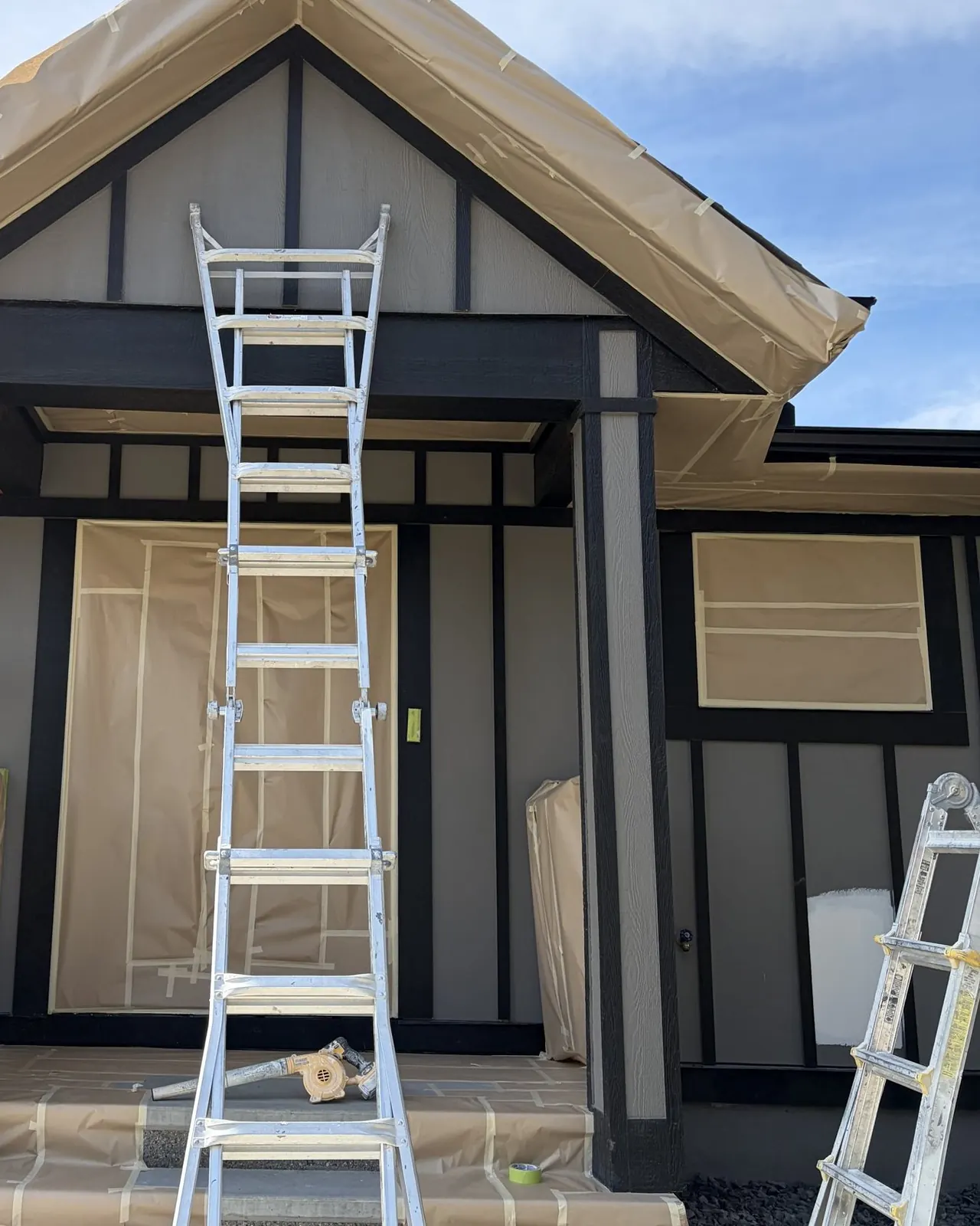 A house entry with windows and door masked in paper, ladders set up for spraying