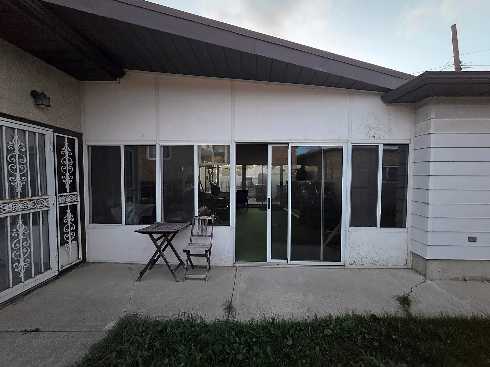 Another side of the stucco sunroom with worn paint before work starts