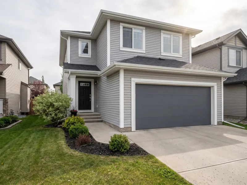 Example of a Calgary two-storey home with a freshly painted black front door and charcoal garage door
